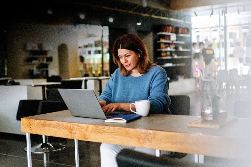 A Nymbus team member working on a laptop in a warm, open workspace.